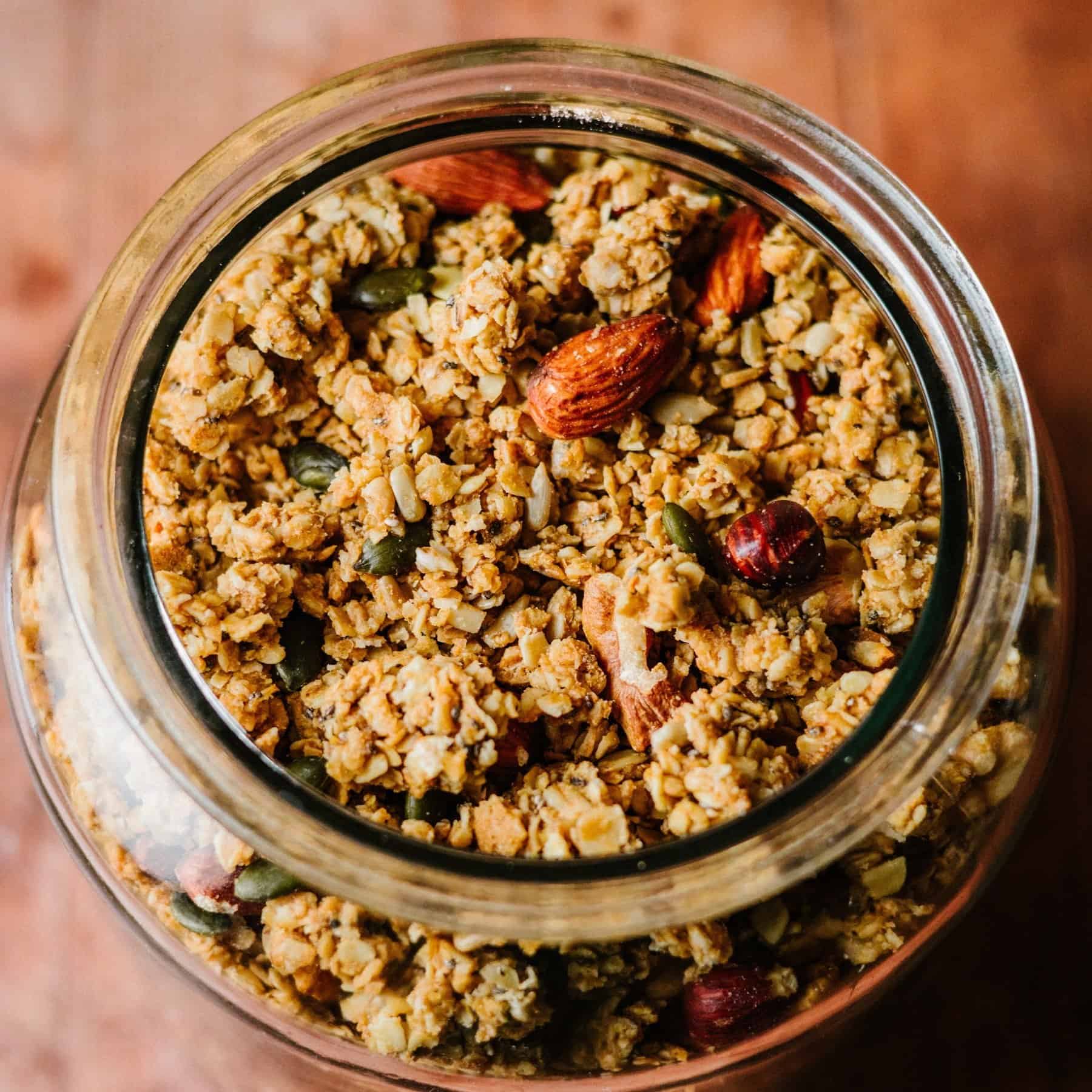 Easy biscoff granola recipe. A glass jar of homemade Biscoff granola with crunchy clusters, nuts, and seeds. Recipes using lotus biscoff spread. Accessible recipes.
