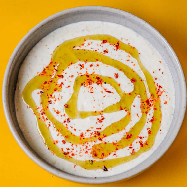 Overhead shot of lemon garlic whipped feta dip in a bowl, drizzled with olive oil and sprinkled with chilli flakes